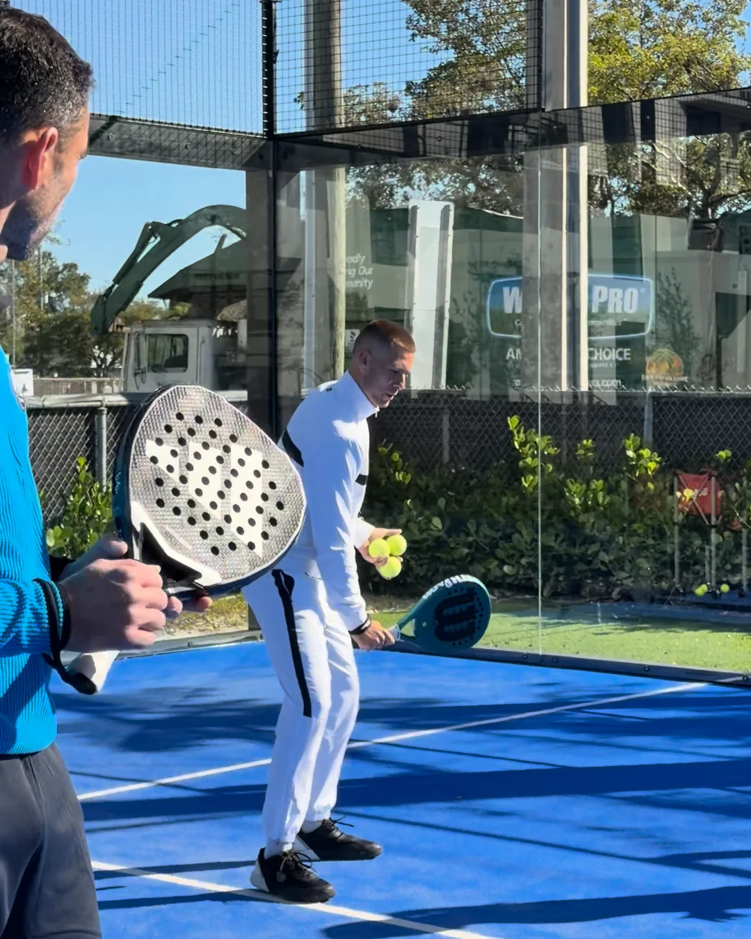 A PadelEdge coach feeding balls to a player working a theme on court